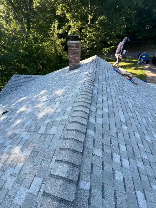 A colonial home mid-reroof with felt paper down, a ladder up and the porch roof tied in